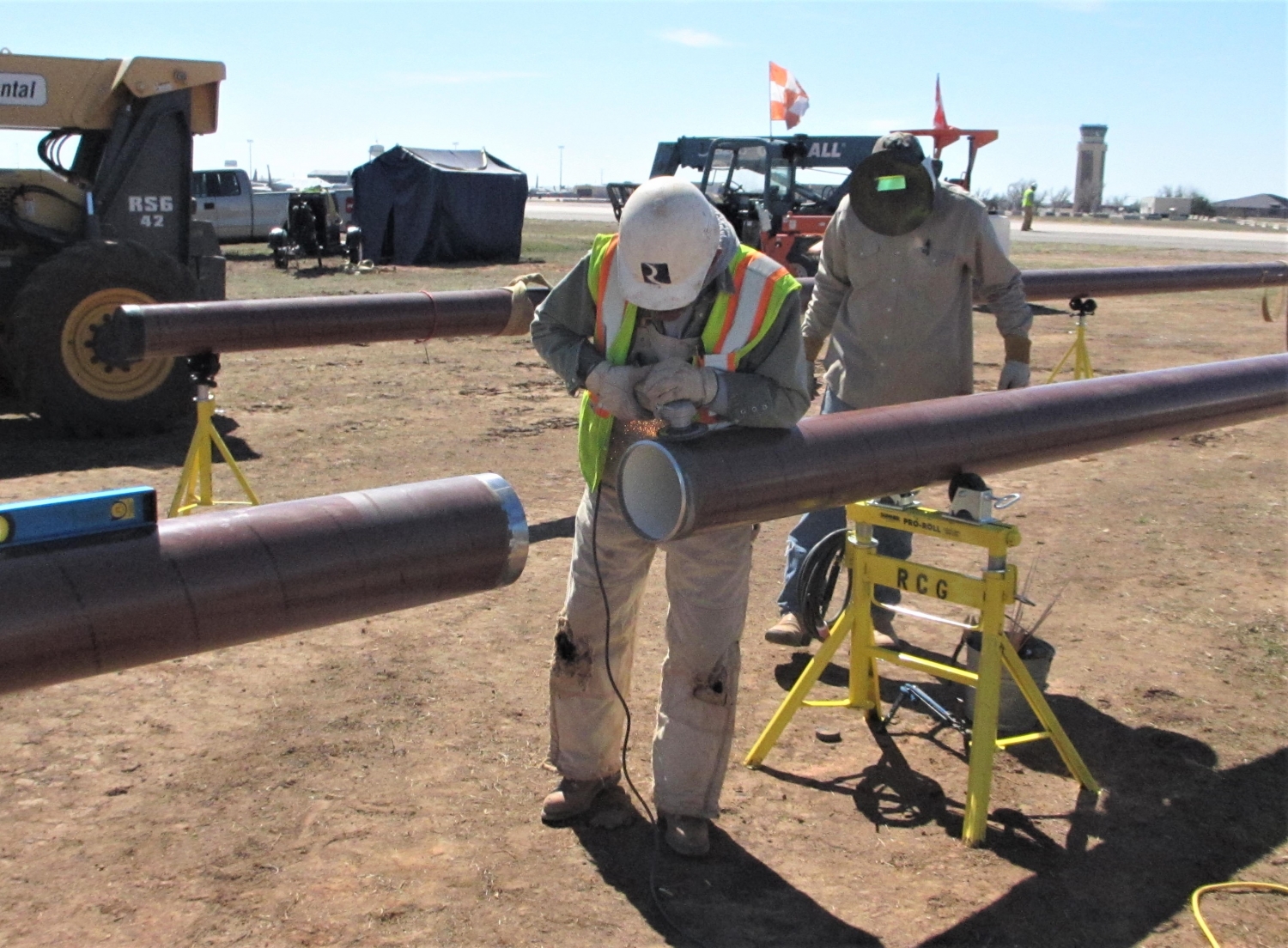 Reliable team members fitting two pieces of a fuel pipeline together.