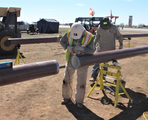 Reliable team members fitting two pieces of a fuel pipeline together.